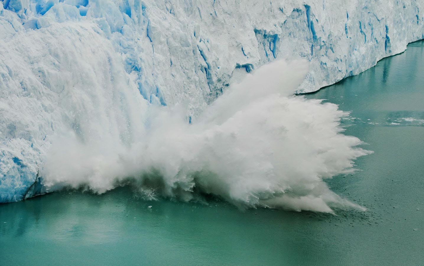 A chunk of ice falling from the glacier, and into the frigid waters below